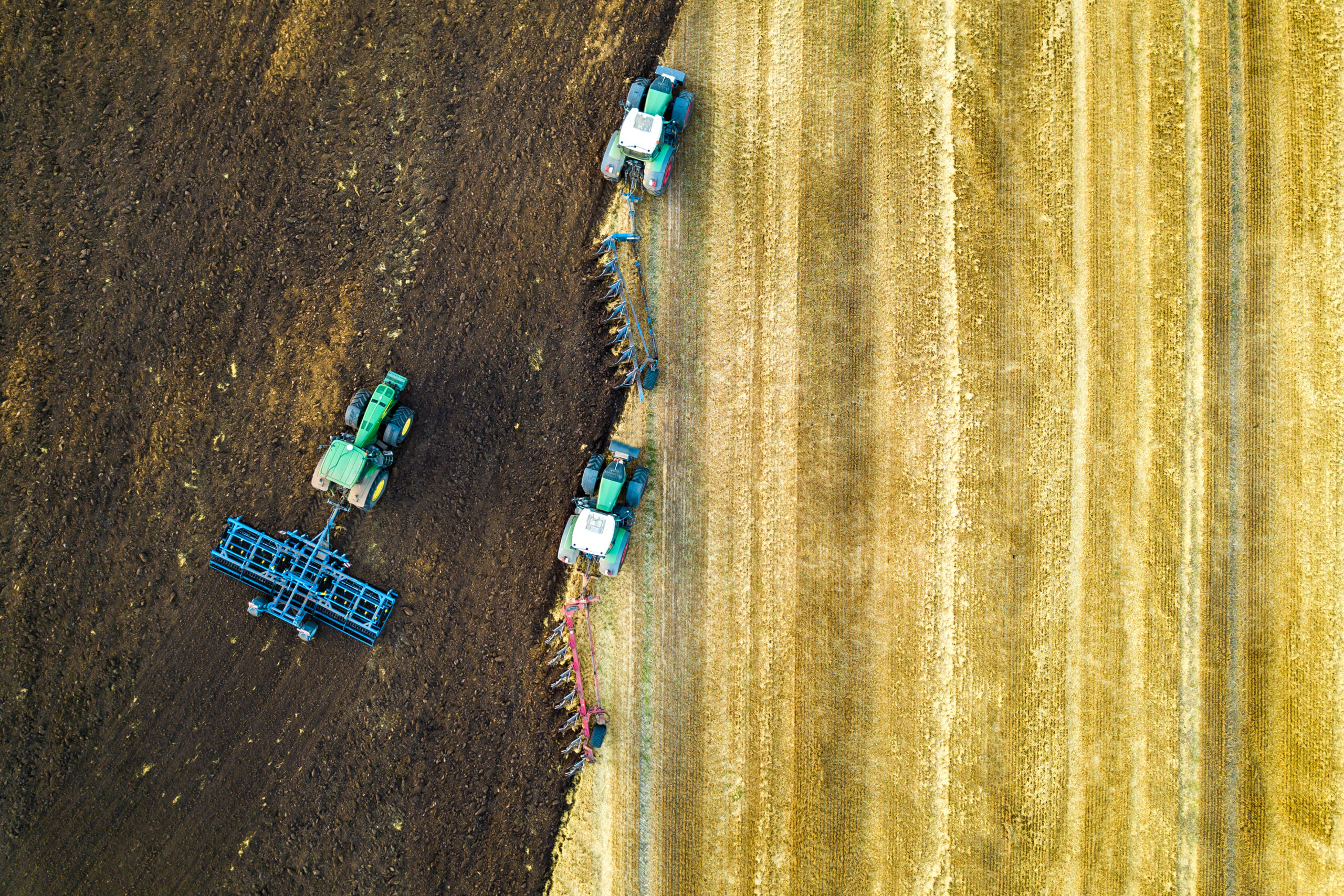 Aerial view of a tractor plowing black agriculture farm field after harvesting in late autumn. Gestió circular dels residus agrícoles i ramaders.